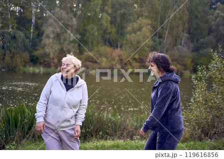 middle-aged woman and her old mother laughing during a morning jog together, for maintaining health by the river in autumn 119616856