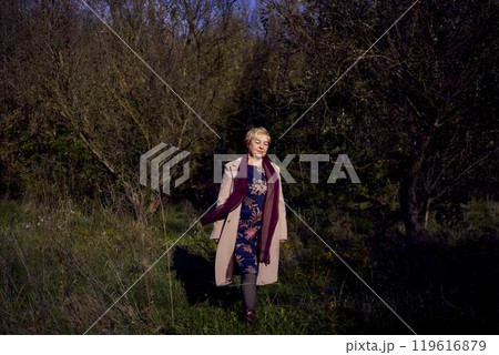 elderly woman with gray hair in light beige coat enjoying nature in autumn forest elderly woman with gray hair in light beige coat enjoying nature in autumn forest 119616879
