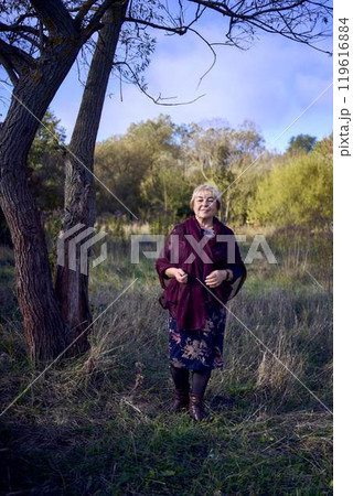 portrait of an elderly woman with gray hair in a dress and shawl in the autumn forest portrait of an elderly woman with gray hair in a dress and shawl in the autumn forest 119616884