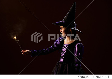 Girl burning sparkler on Halloween night 119616901