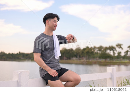 Smiling athlete checking fitness tracker after outdoor workout. Healthy lifestyle concept Smiling athlete checking fitness tracker after outdoor workout. Healthy lifestyle concept 119618061