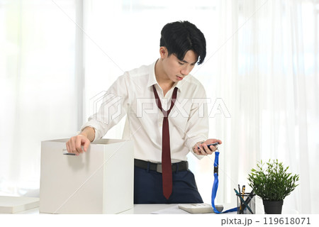 Frustrated man looking at his ID badge while preparing to leave his job Frustrated man looking at his ID badge while preparing to leave his job 119618071