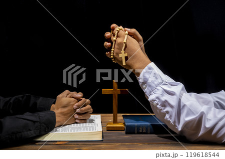 Man praying together with rosary beads, religion cross and holy bible on wooden table. Symbol of faith and worship in God. People christianity prayer in church 119618544