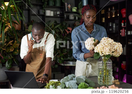 Waist up portrait of two young people working together in flower shop and managing delivery orders 119620256