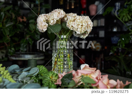 Background image of elegant floral composition with white hydrangea flowers in glass vase on table in flower shop with low lighting copy space 119620275