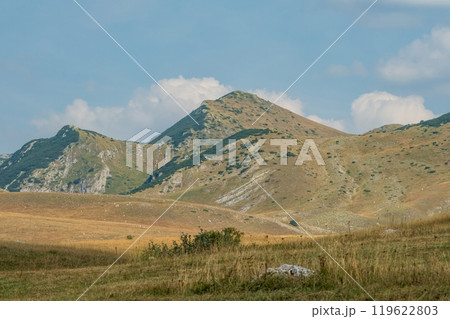 Grassy mountain slopes with rocky terrain under blue sky. Durmitor National Park Montenegro Grassy mountain slopes with rocky terrain under blue sky. Durmitor National Park Montenegro 119622803