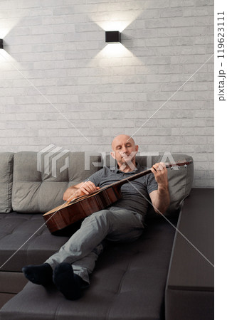 man guitarist playing guitar at home. Relaxing and sitting on sofa 119623111