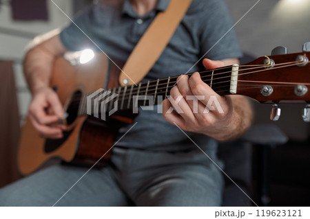 Man paying a acoustic guitar in sound studio. Male musician playing music instrument Man paying a acoustic guitar in sound studio. Male musician playing music instrument 119623121