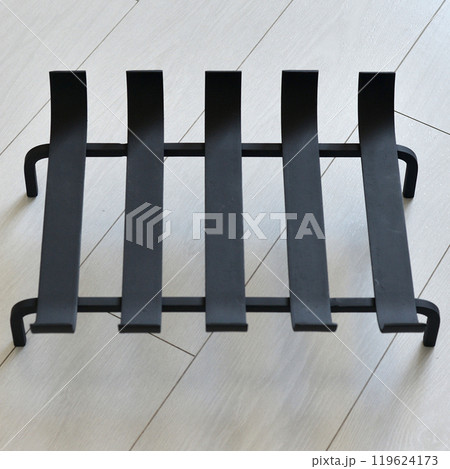 An object photo shoot of black grilles for fireplaces on a light background in the interior. An object photo shoot of black grilles for fireplaces on a light background in the interior. 119624173