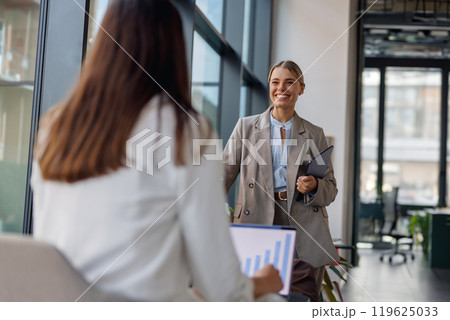 A Professional Business Meeting Happening with Smiling Colleagues in a Modern Office Environment A Professional Business Meeting Happening with Smiling Colleagues in a Modern Office Environment 119625033