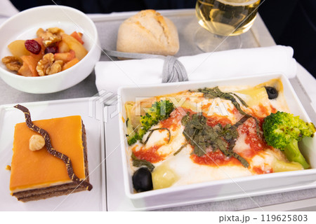おいしいビジネスクラスの機内食リコッタとほうれん草のカネロニとシャンパン、チョコレートケーキ 119625803