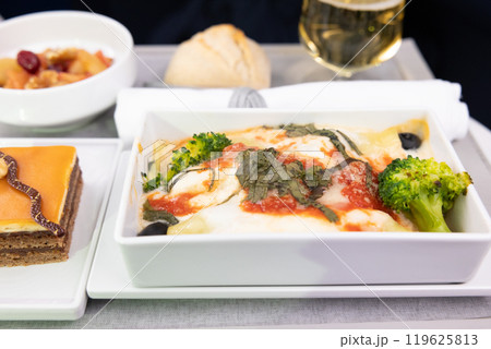 おいしいビジネスクラスの機内食リコッタとほうれん草のカネロニとシャンパン、チョコレートケーキ 119625813