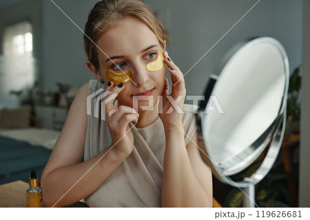 Applying Gold Eye Patches for Soothing Skin Care Routine Applying Gold Eye Patches for Soothing Skin Care Routine 119626681