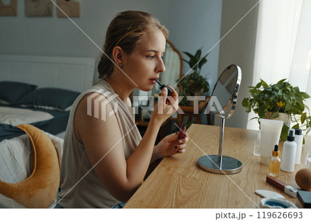 Woman Applying Makeup in Modern Bedroom Setting 119626693