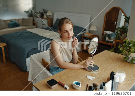 Young Woman Applying Makeup at Vanity Table Young Woman Applying Makeup at Vanity Table 119626701