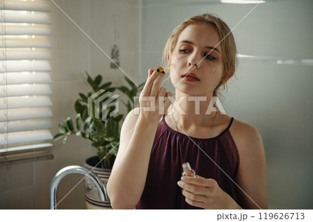 Applying Makeup in Modern Minimalist Bathroom Setting Applying Makeup in Modern Minimalist Bathroom Setting 119626713