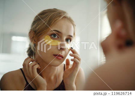 Woman Applying Skincare Patch Under Eye 119626714