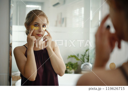 Woman Applying Skincare Mask in Bright Bathroom 119626715