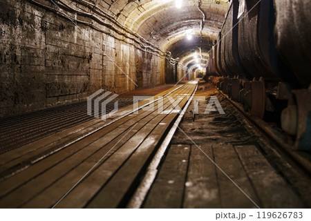 A Captivating View of an Old Rusty Mine Tunnel with Tracks and Vintage Mining Carts Inside A Captivating View of an Old Rusty Mine Tunnel with Tracks and Vintage Mining Carts Inside 119626783