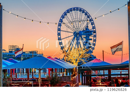 Stunning Ferris wheel illuminated at sunset with vibrant sky and restaurant view at amusement park Stunning Ferris wheel illuminated at sunset with vibrant sky and restaurant view at amusement park 119626826