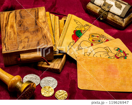 deck of medieval italian board playing cards with a blank and white card, on the table along with coins and wooden card holder 119626947