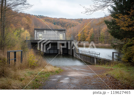 Hydroelectric dam with a focus on the power generation turbines and surrounding nature. A dam is built in a scenic forest by a tranquil lake 119627465