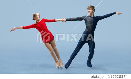 Figure skating duo executes perfect lift during their performance against cold blue background. Graceful lift pose in competitive figure skating Figure skating duo executes perfect lift during their performance against cold blue background. Graceful lift pose in competitive figure skating 119628374