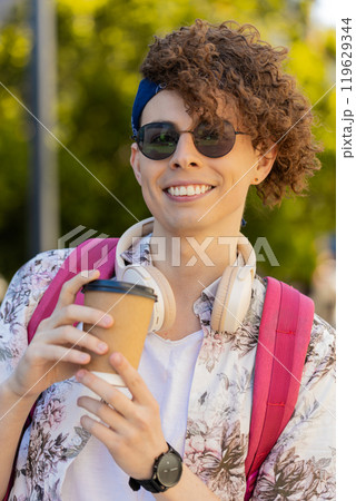 Smiling man tourist enjoying morning coffee hot drink relaxing, taking a break on urban city street 119629344