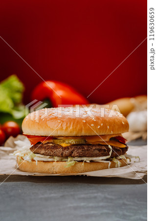 Juicy cheeseburger with fresh vegetables and melted cheese on sesame bun, fast-food lovers Juicy cheeseburger with fresh vegetables and melted cheese on sesame bun, fast-food lovers 119630659