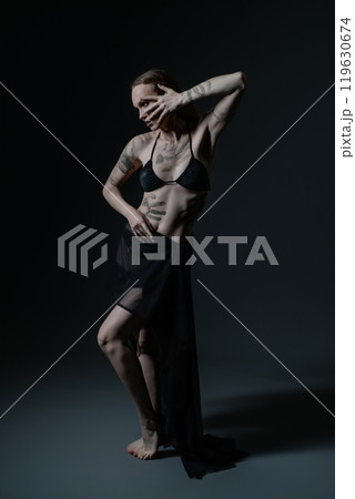 Artistic expression of a tattooed model posing dramatically in low light 119630674
