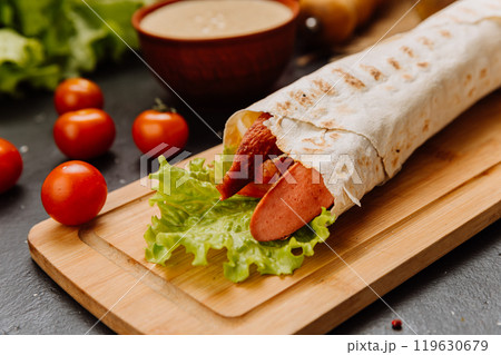 Grilled sausage wrap with fresh lettuce, a perfect quick snack or meal for on-the-go moments Grilled sausage wrap with fresh lettuce, a perfect quick snack or meal for on-the-go moments 119630679