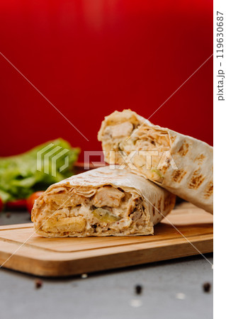 Freshly grilled chicken wrap cut in half, revealing creamy filling.Perfect fast-food snack 119630687