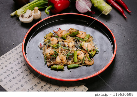 Stir-fried chicken with vegetables and glass noodles, garnished with sesame seeds for a healthy meal 119630699