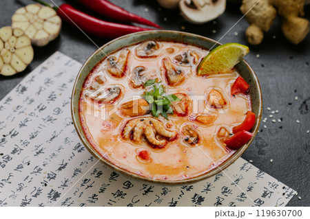 Spicy Tom Yum soup with seafood, mushrooms, and chili served with lime and herbs in Asian style 119630700