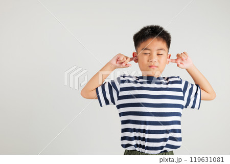 Asian young kid boy expression of pain and frustration is evident as she covers ears and closes her eyes with fingers to escape the loud noise in studio shot isolated white background, primary child Asian young kid boy expression of pain and frustration is evident as she covers ears and closes her eyes with fingers to escape the loud noise in studio shot isolated white background, primary child 119631081