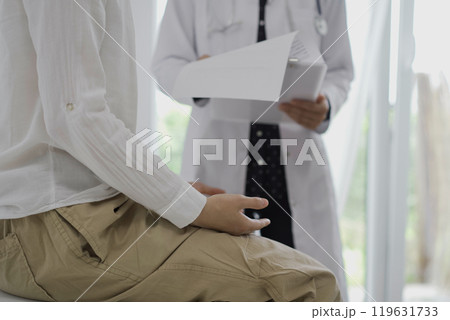 Doctor and a patient discussing something. The female physician, wearing a white medical coat standing with a clipboard during a consultation in the clinic, close up. Medicine concept 119631733