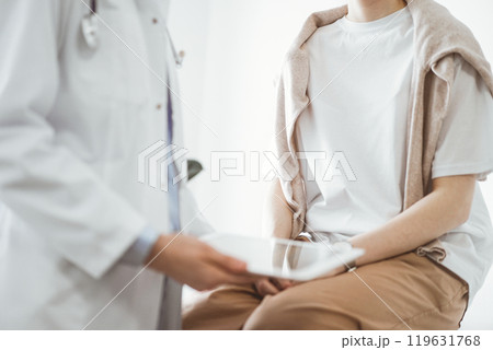 Doctor and patient in clinic. Friendly physician using tablet computer near a young woman. Medicine concept 119631768