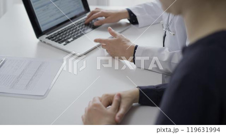 Doctor and a patient are discussing health while sitting in clinic. The female physician is using laptop computer. Medicine and science 119631994