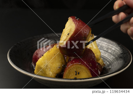 大学芋 たれを絡めた大学芋を箸で持ち上げる 119634434