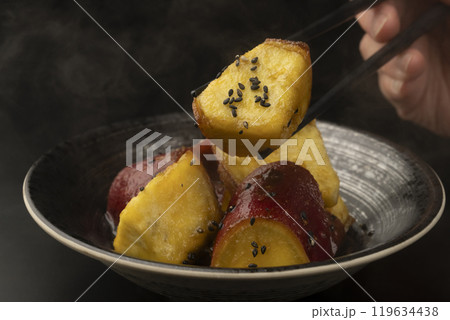 大学芋 たれを絡めた大学芋を箸で持ち上げる 119634438
