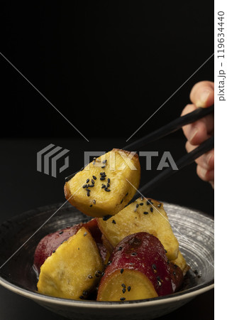 大学芋 たれを絡めた大学芋を箸で持ち上げる 119634440