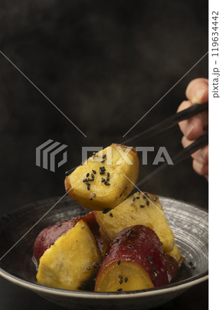 大学芋 たれを絡めた大学芋を箸で持ち上げる 119634442