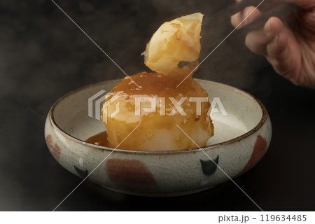 ふろふき大根　味噌だれをかけたふろふき大根を箸で持ち上げる 119634485