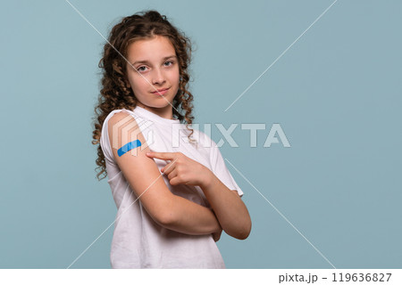 Girl pointing at blue bandage after receiving vaccination. Girl pointing at blue bandage after receiving vaccination. 119636827