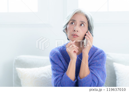 スマートフォンで会話をする困った表情の女性 119637010