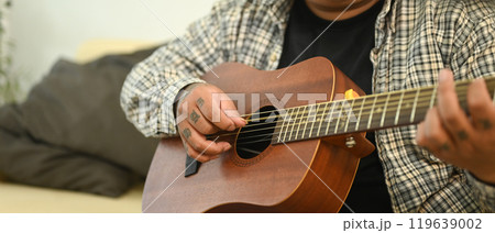 Close up of man playing acoustic guitar. Leisure activity and hobby concept 119639002