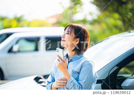 車の横でスマホで持つ女性 車の横でスマホで持つ女性 119639012