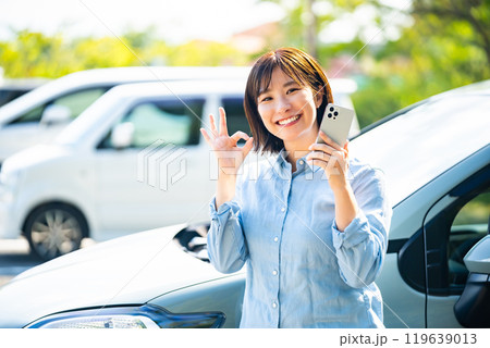 車の横でスマホで電話をかける女性 119639013