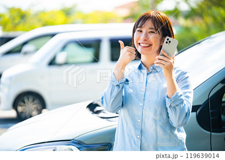 車の横でスマホで電話をかける女性 119639014