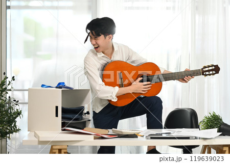 Energetic employee in white shirt with necktie around his head enjoying a music break amidst busy workday 119639023